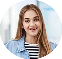 Smiling young woman with long straight light brown hair wearing a denim jacket and striped shirt.